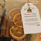 Halloween-themed simmer potpourri with oranges, cinnamon sticks, and a label on a decorative background.